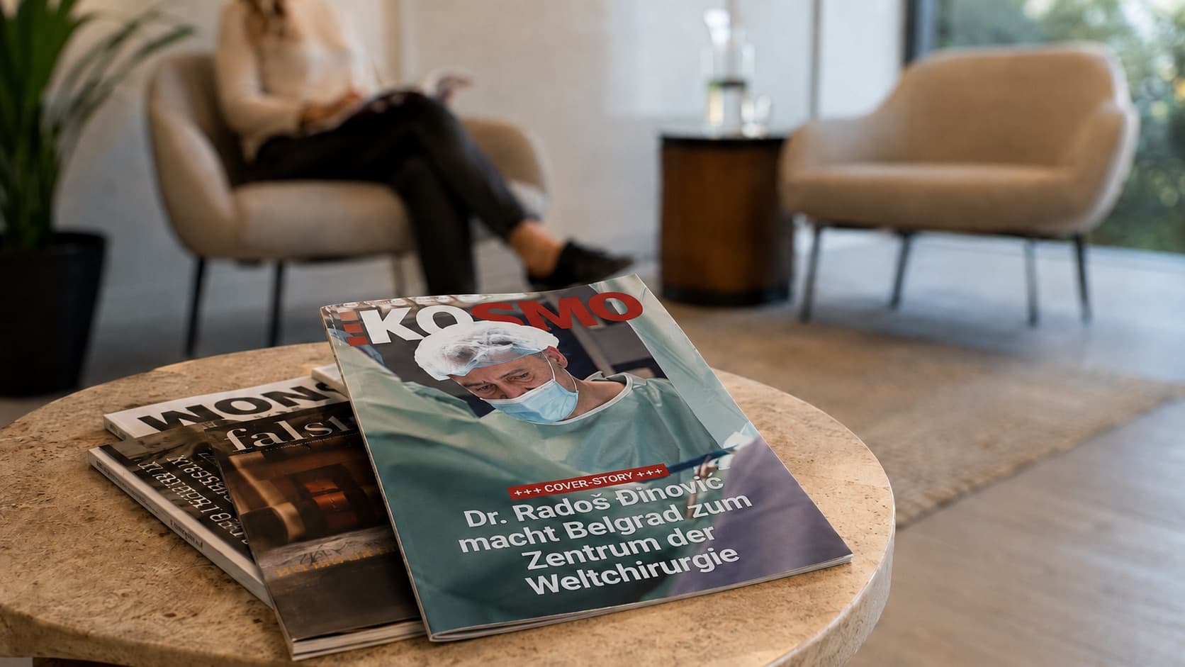 Ein KOSMO-Heft liegt auf dem Tisch eines Wartebereichs, im Hintergrund sitzt eine lesende Frau